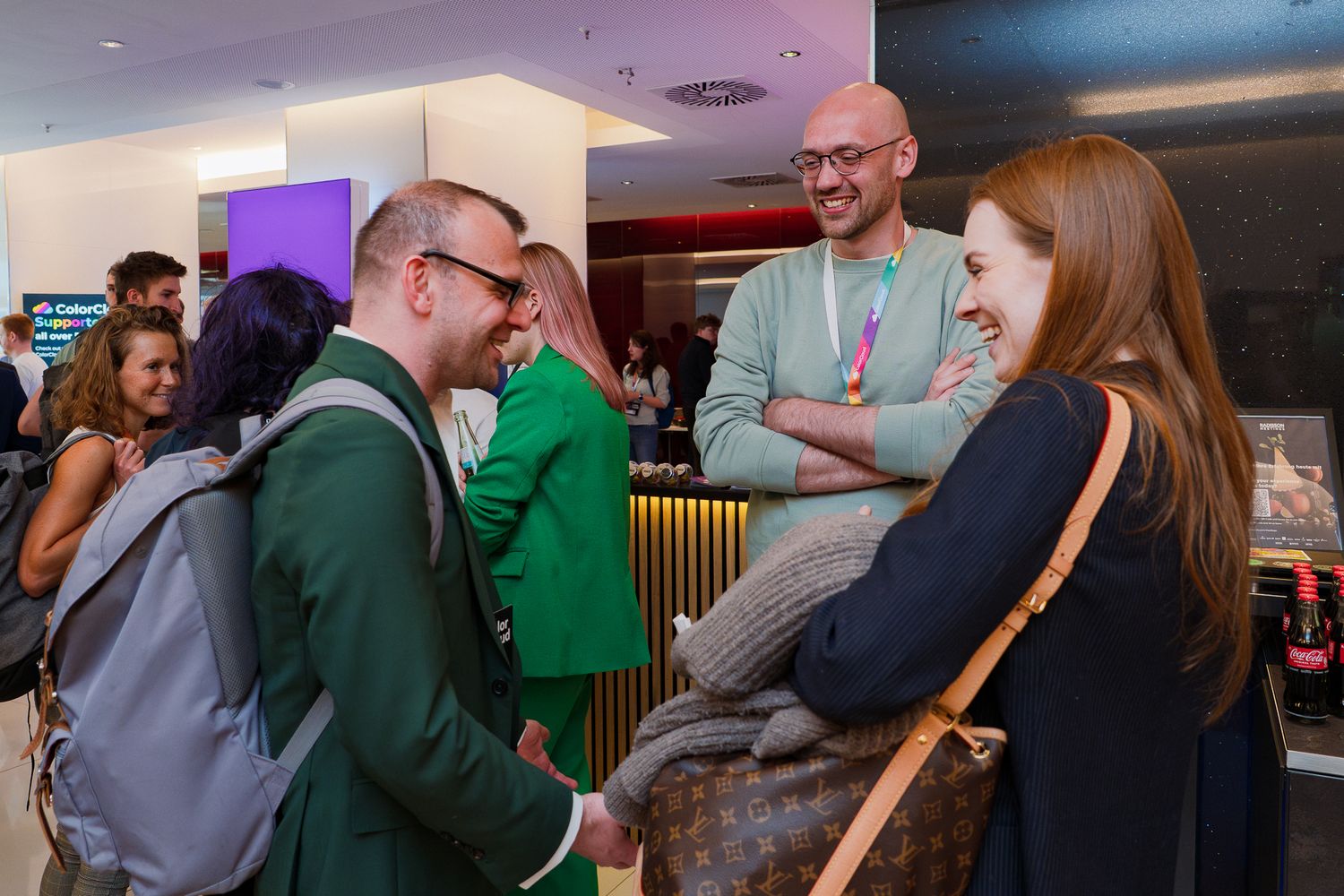 Zwei Männer und eine Frau unterhalten sich lachend im Foyer der ColorCloud-Konferenz 2025