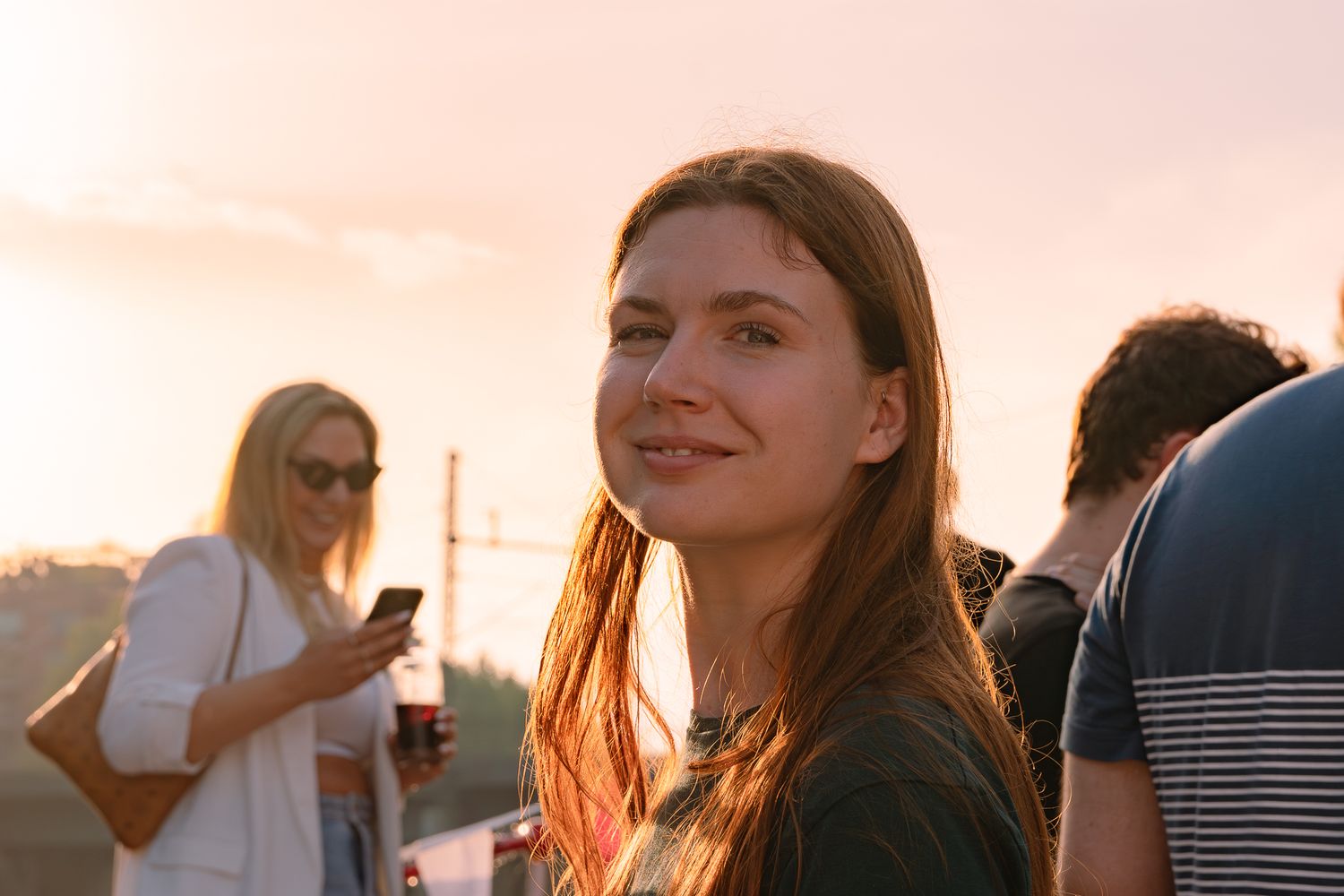 Rothaarige Junge Frau wird von der Abendsonne angeschienen und lächelt in die Kamera