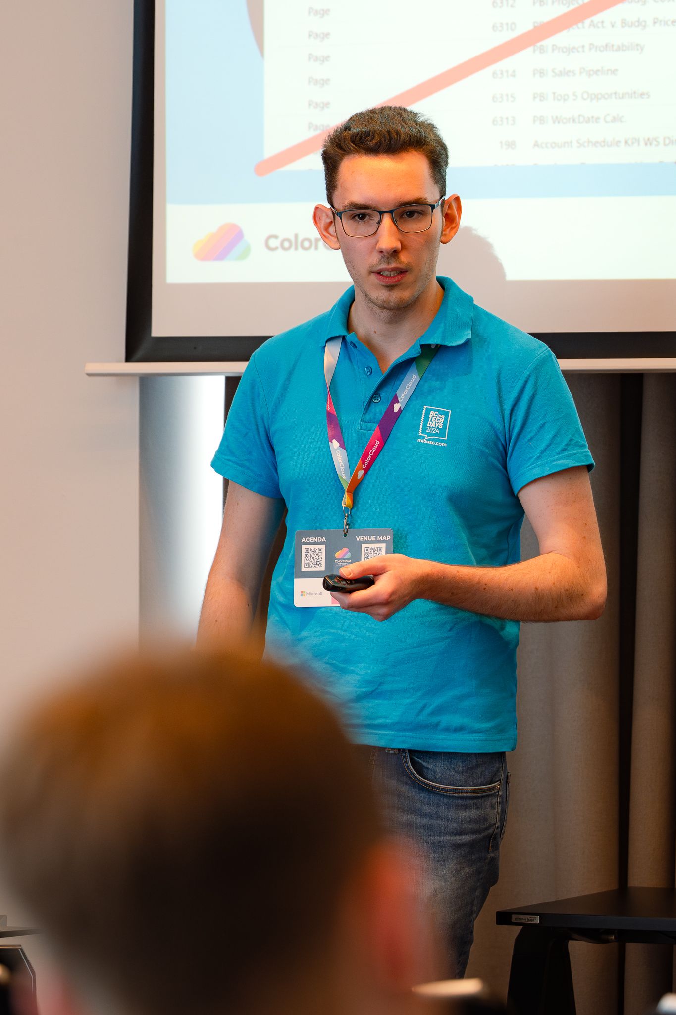 Christian Hovenbitzer hält einen Präsentations-Pointer in der Hand und hält vor den Teilnehmenden der ColorCloud-Konferenz einen Vortrag