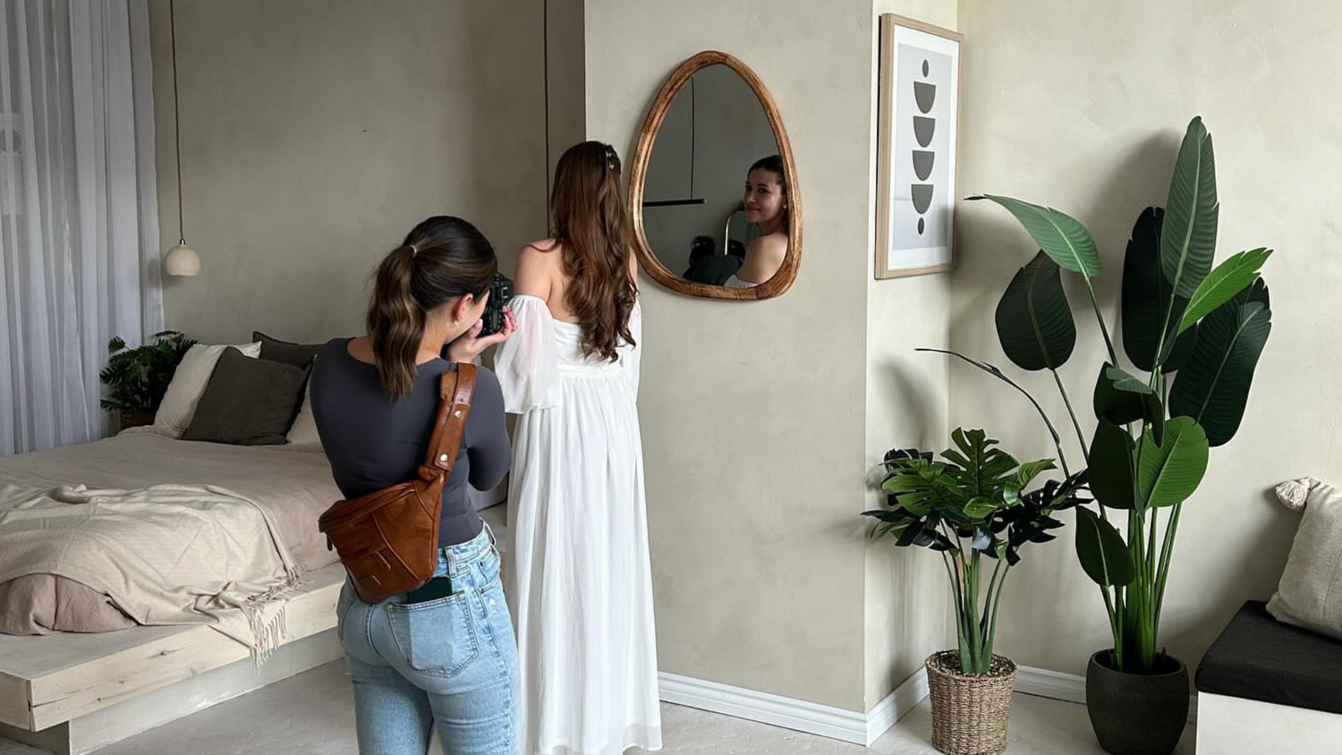 A photographer wearing blue jeans and a grey shirt taking a photo of a bride in a wedding dress with puffy sleeves. The 
