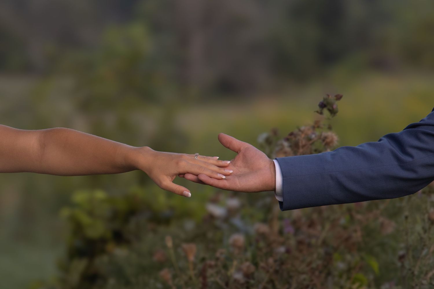 A woman's and a man's hand reaching out for the other.