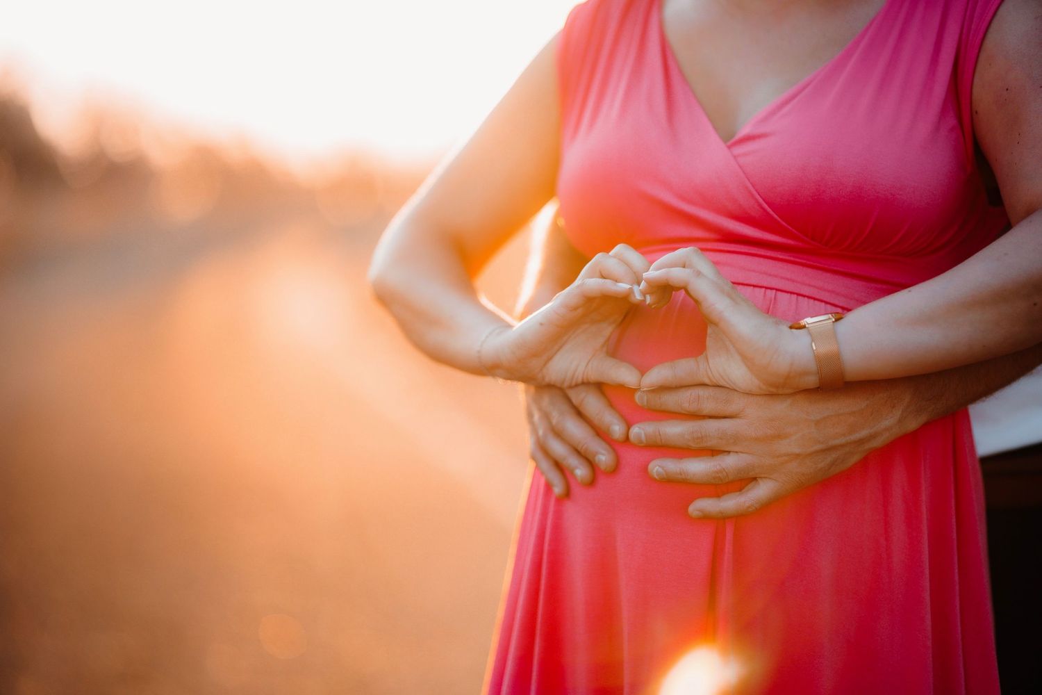 A series of maternity photos showing a pregnant woman in a coral dress touching her belly against different backgrounds.