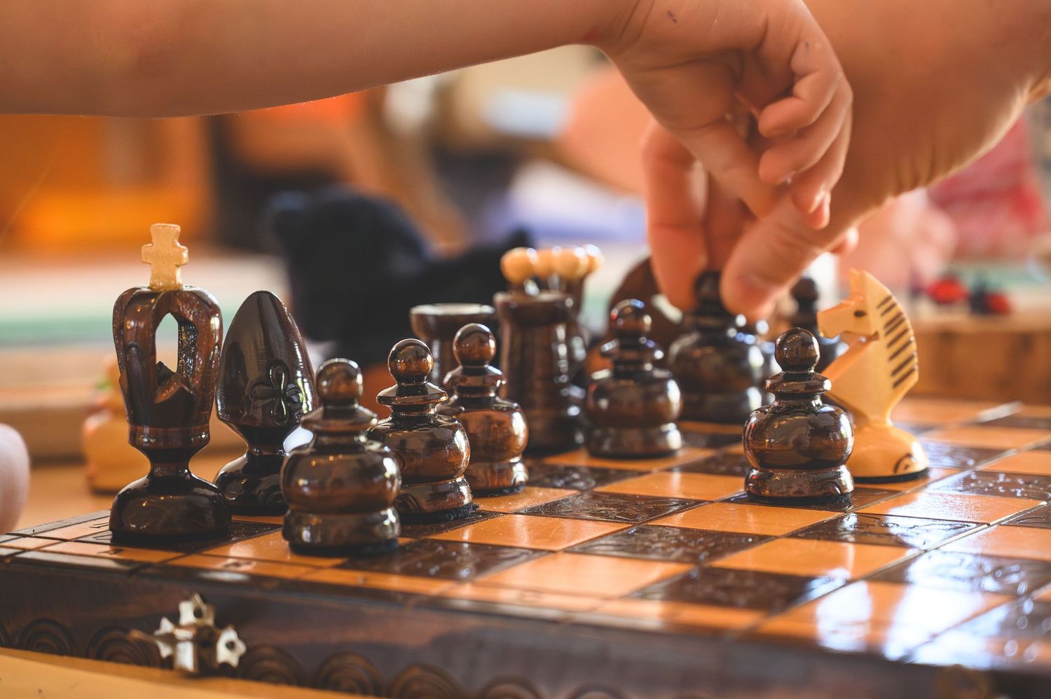 A hand moves a wooden knight chess piece on a classic wooden chessboard during an intense game of chess.