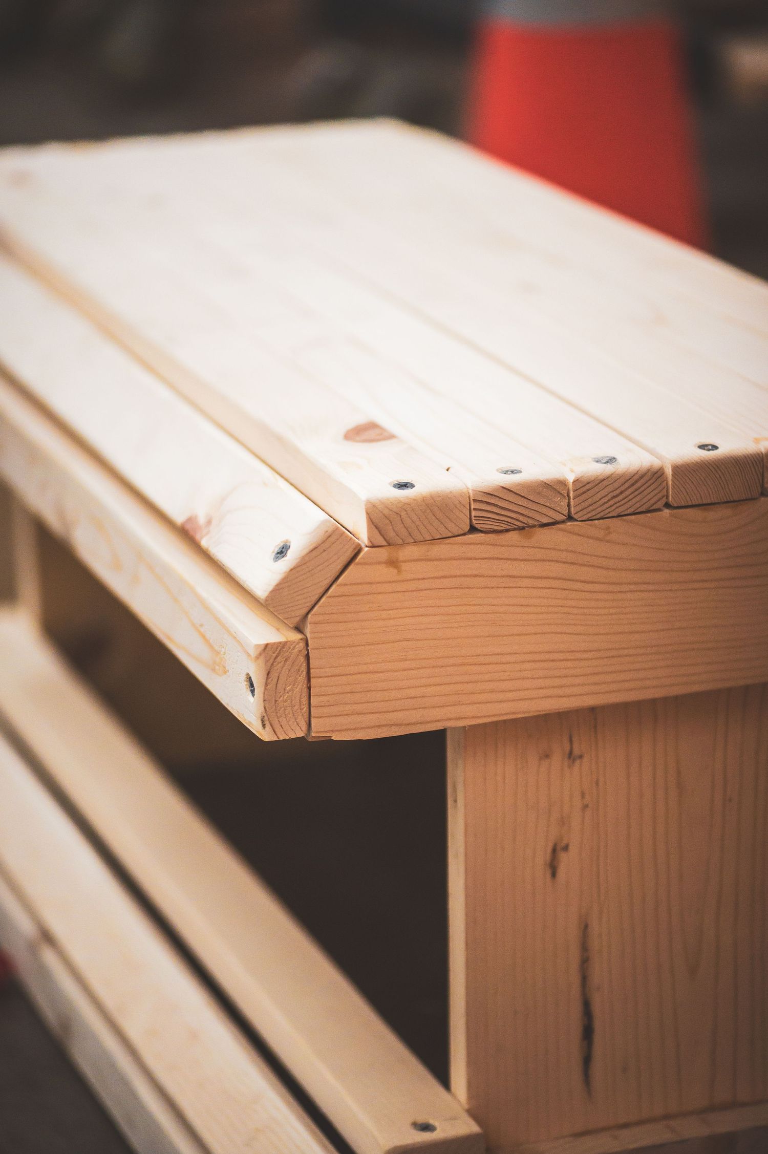 Close-up of a freshly crafted wooden bench corner showcasing precise joinery and smooth pine wood construction.