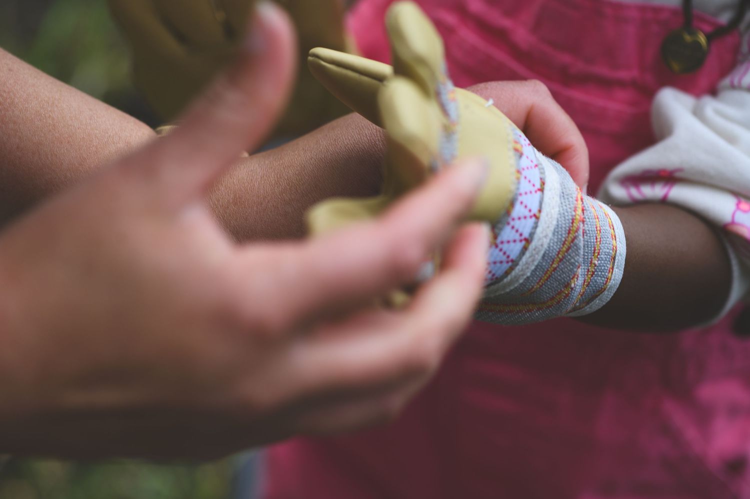Close-up of children's hands holding a small green snake, with a colorful bracelet visible on one wrist.
