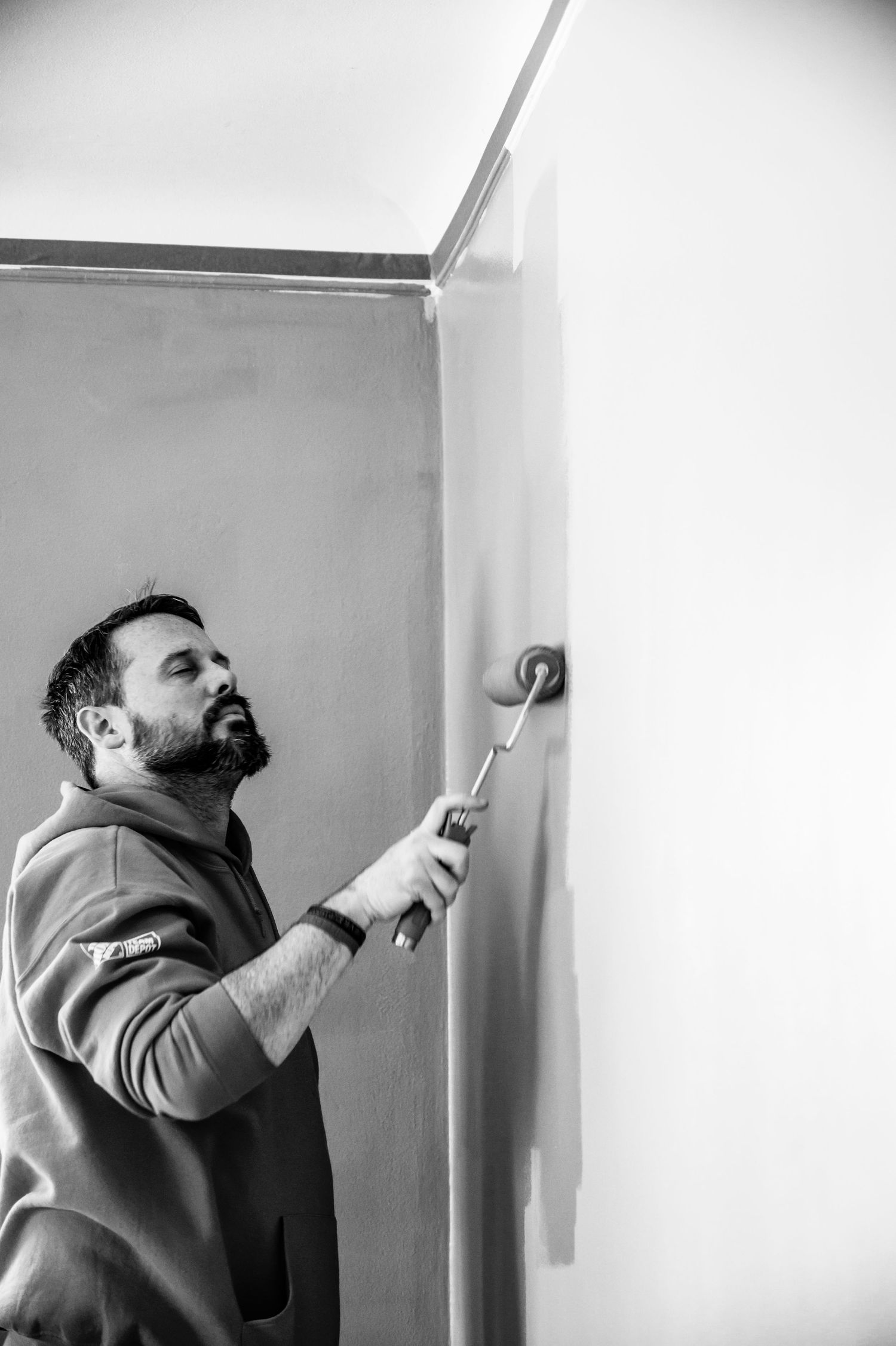 Person in Home Depot uniform using a paint roller on an interior wall.