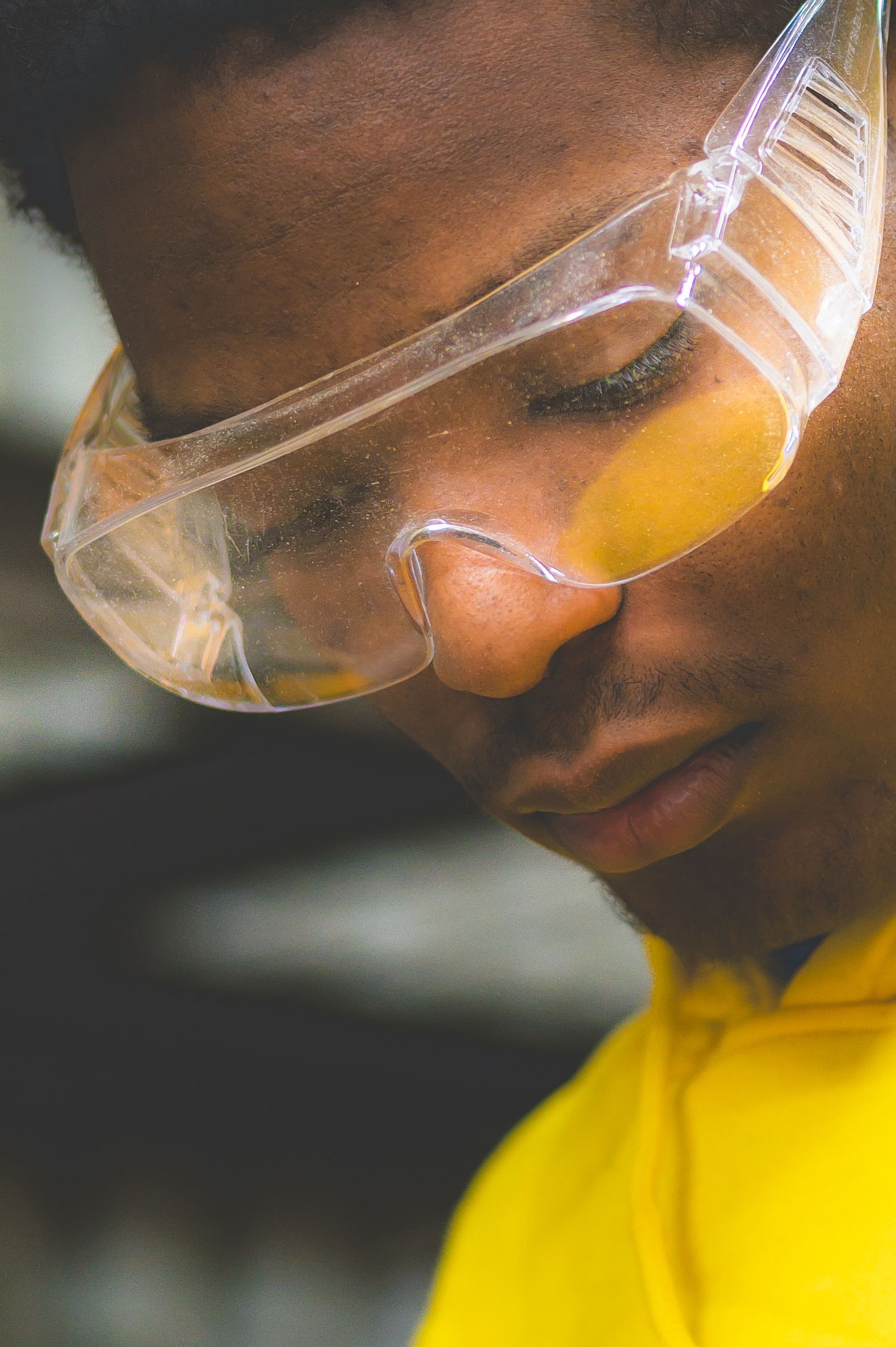 Close-up portrait wearing yellow shirt and protective clear safety glasses with orange tint.