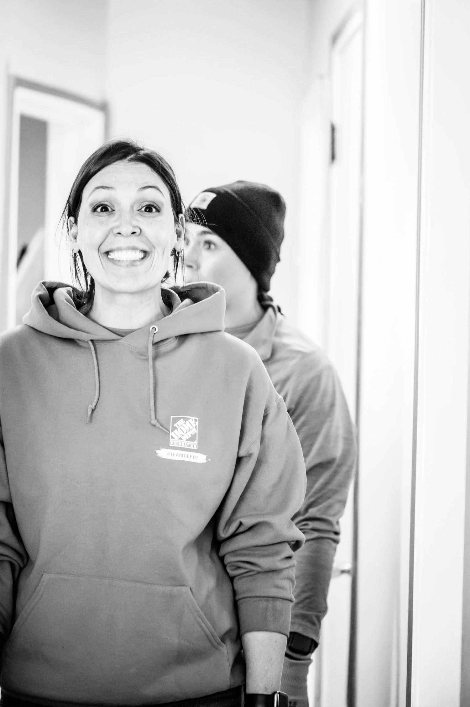 Two volunteers in hooded sweatshirts pose together during a home improvement project.