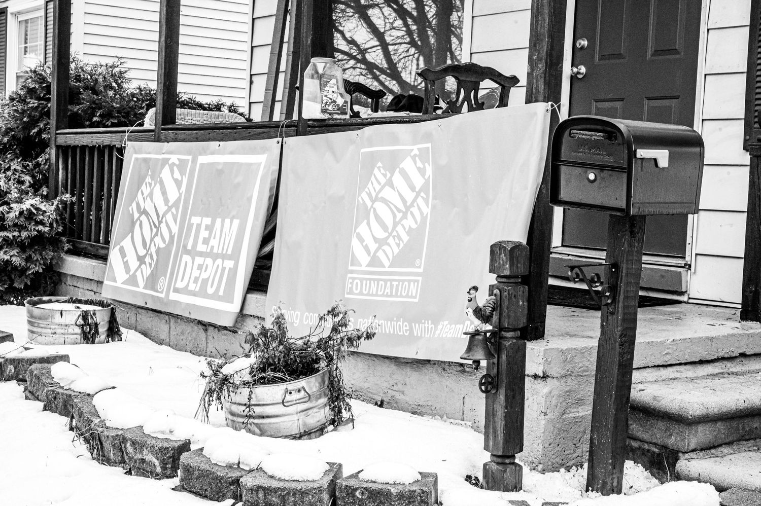 Black and white photo of Home Depot banners displayed on a house porch.