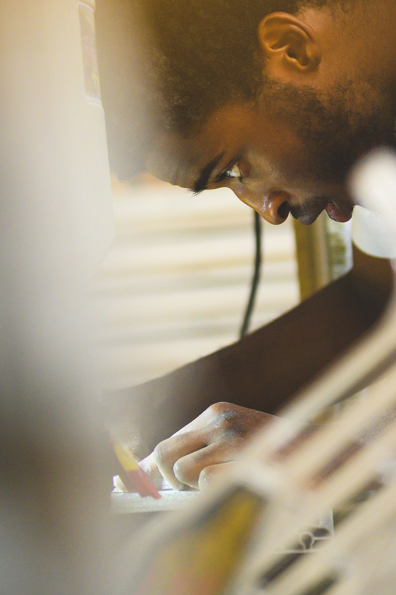 A blurred artistic photograph shows out-of-focus student working on a saw machine.