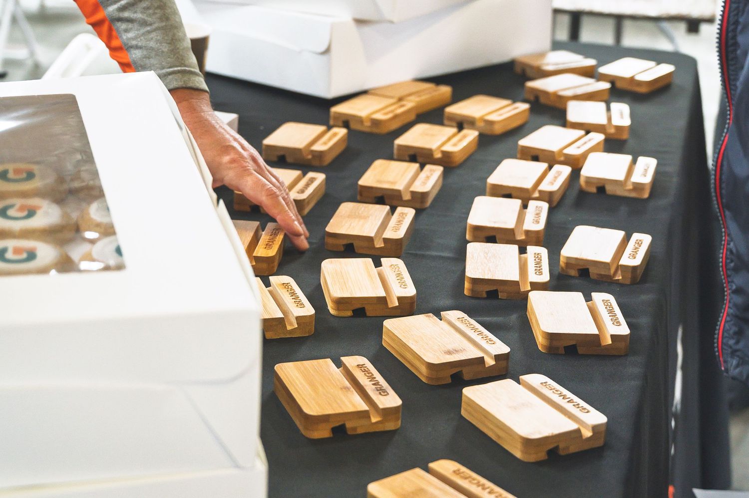 Multiple wooden business card holders arranged on black display table at event or trade show.