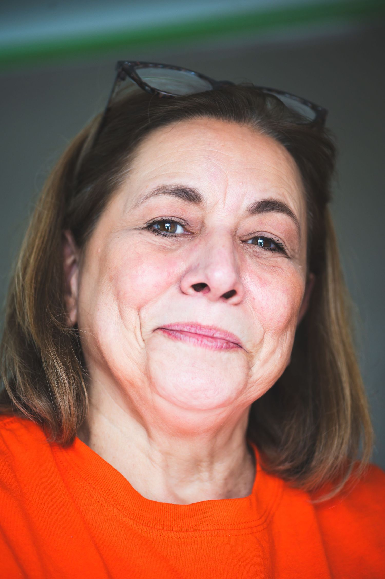 Portrait of woman in bright orange sweater smiling at camera.