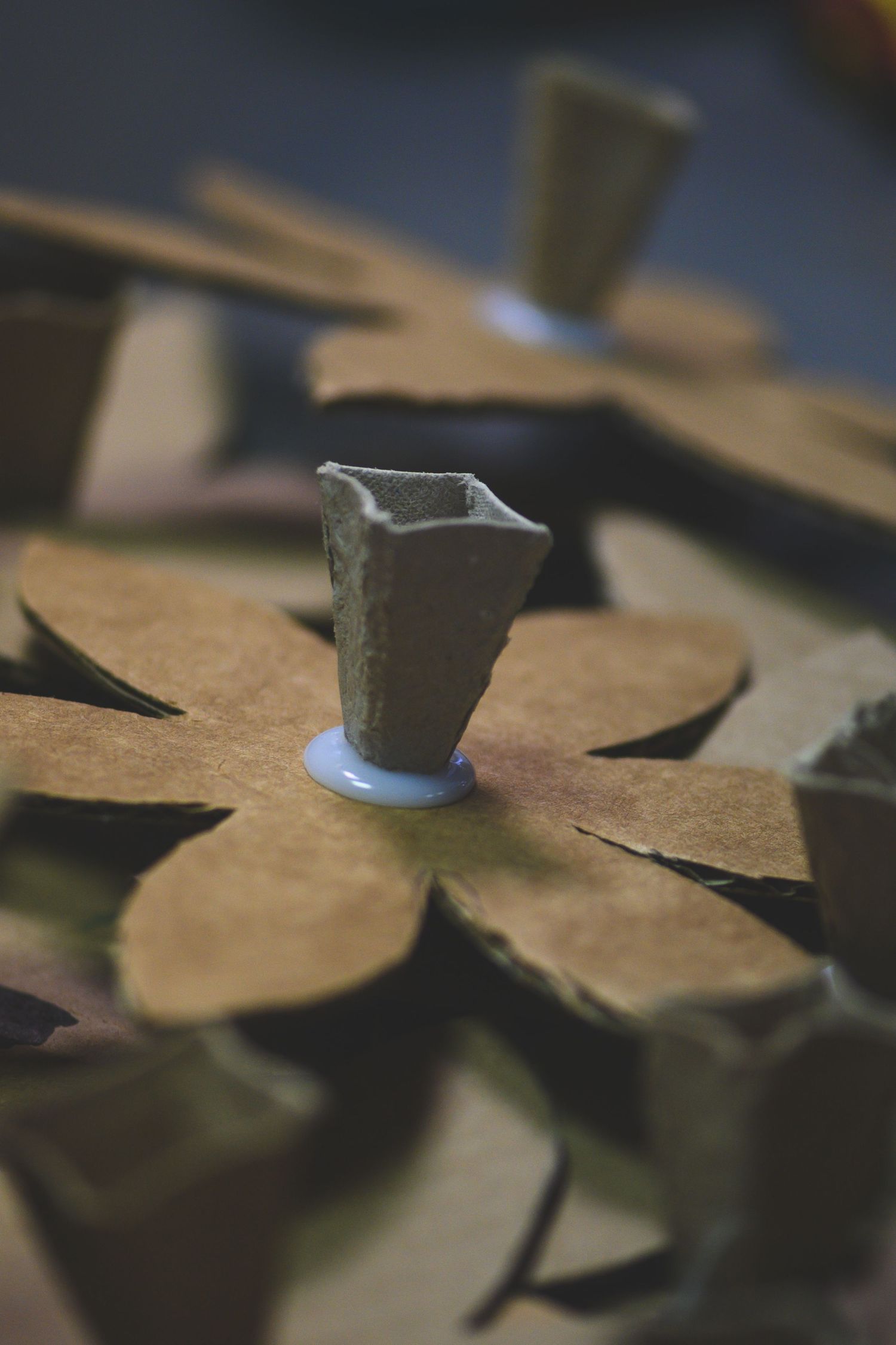 Close-up of small ceramic vases placed on decorative cardboard flower cutouts arranged on a surface.