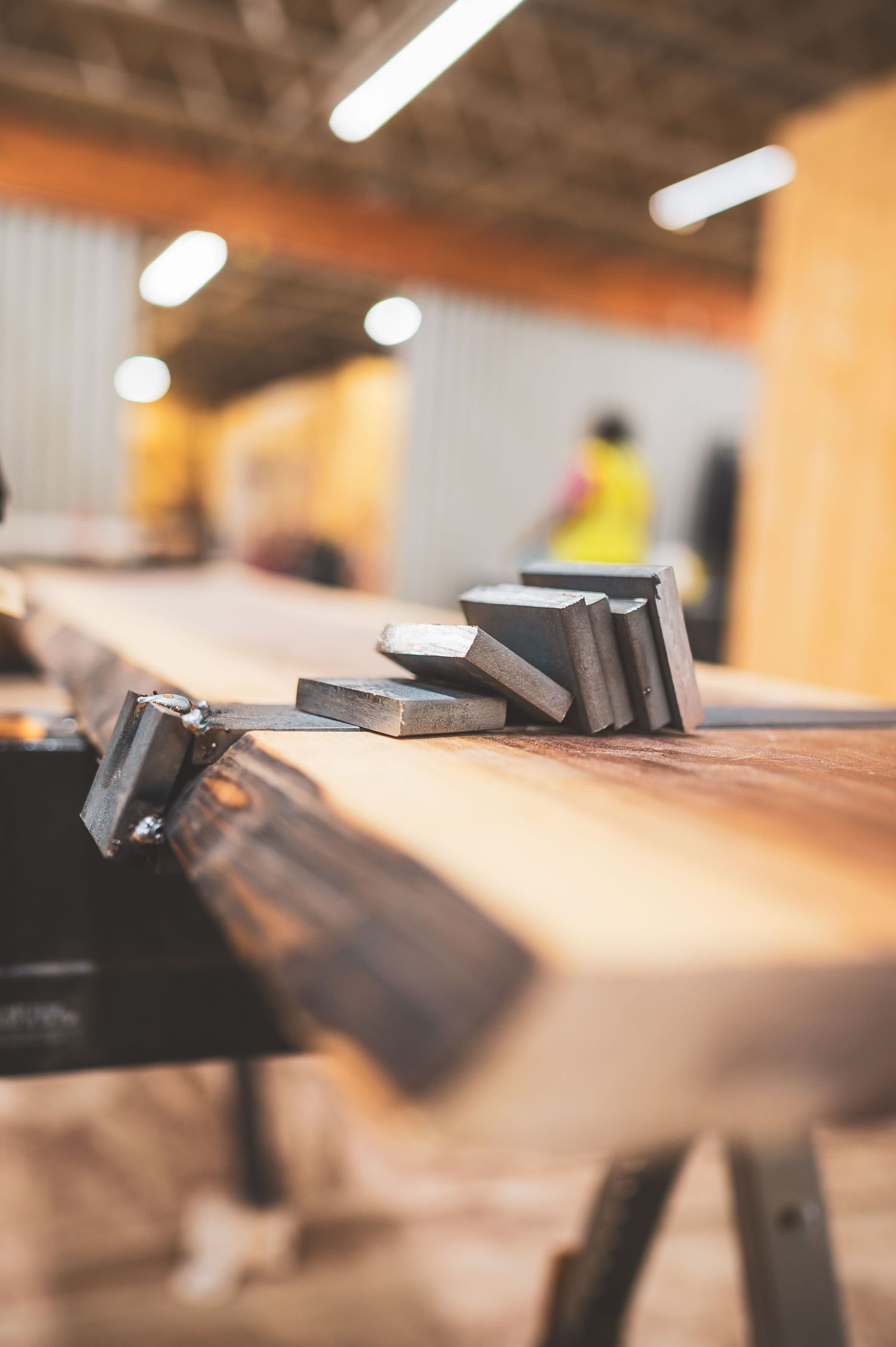 Metal clamps and blocks on a live edge wooden plank in a woodworking workshop.