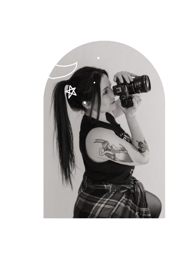 Black and white photo of a photographer holding a camera against a dreamy background with moon and stars decorations.