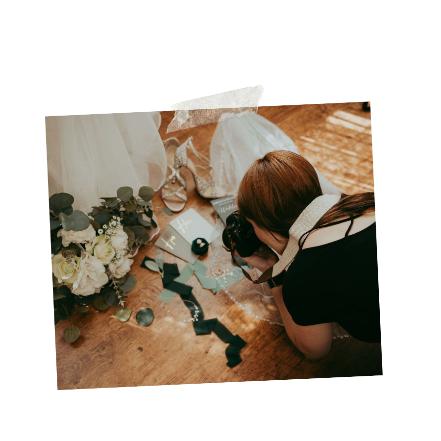 A person in black working on floral arrangements with white flowers and greenery on a wooden surface.