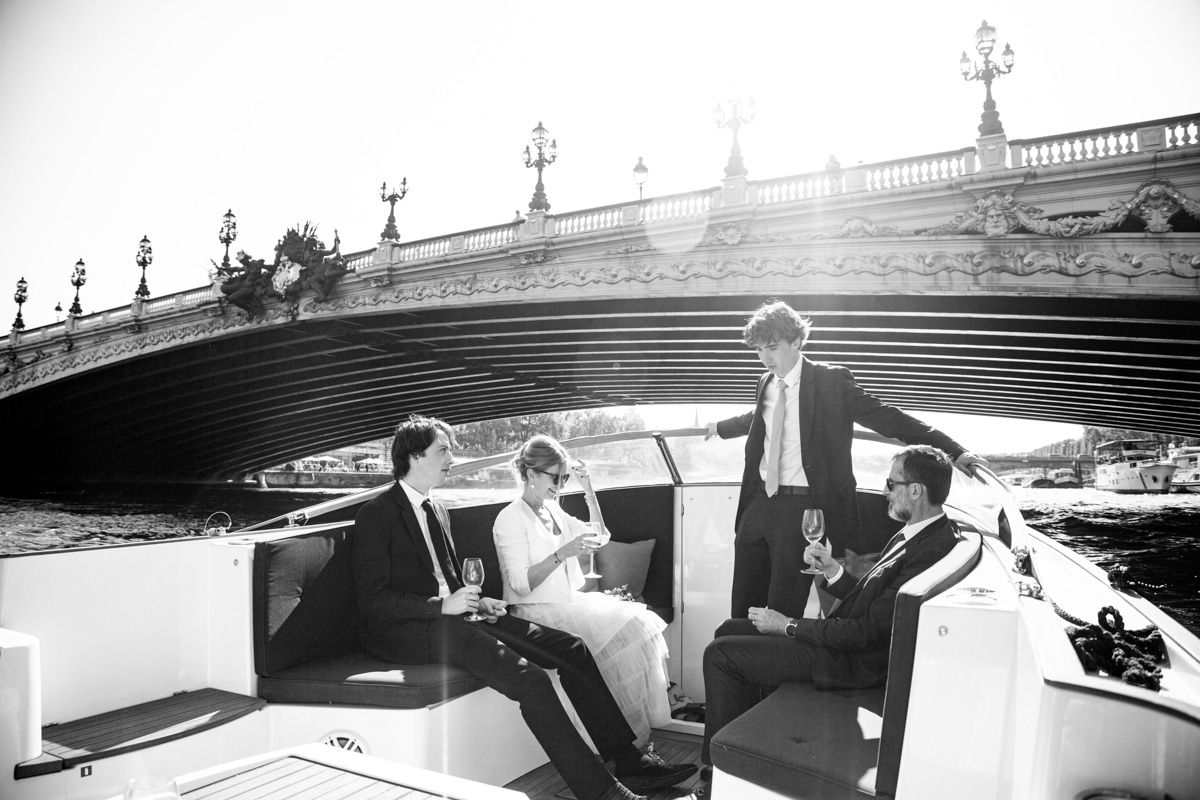 People enjoying a scenic boat ride under an ornate bridge along the Seine River in Paris.