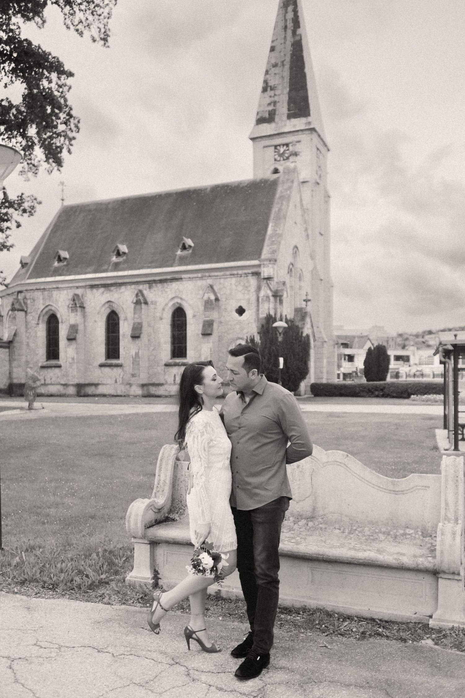 A sequence of black and white photos showing a couple walking together outside a historic white church building.