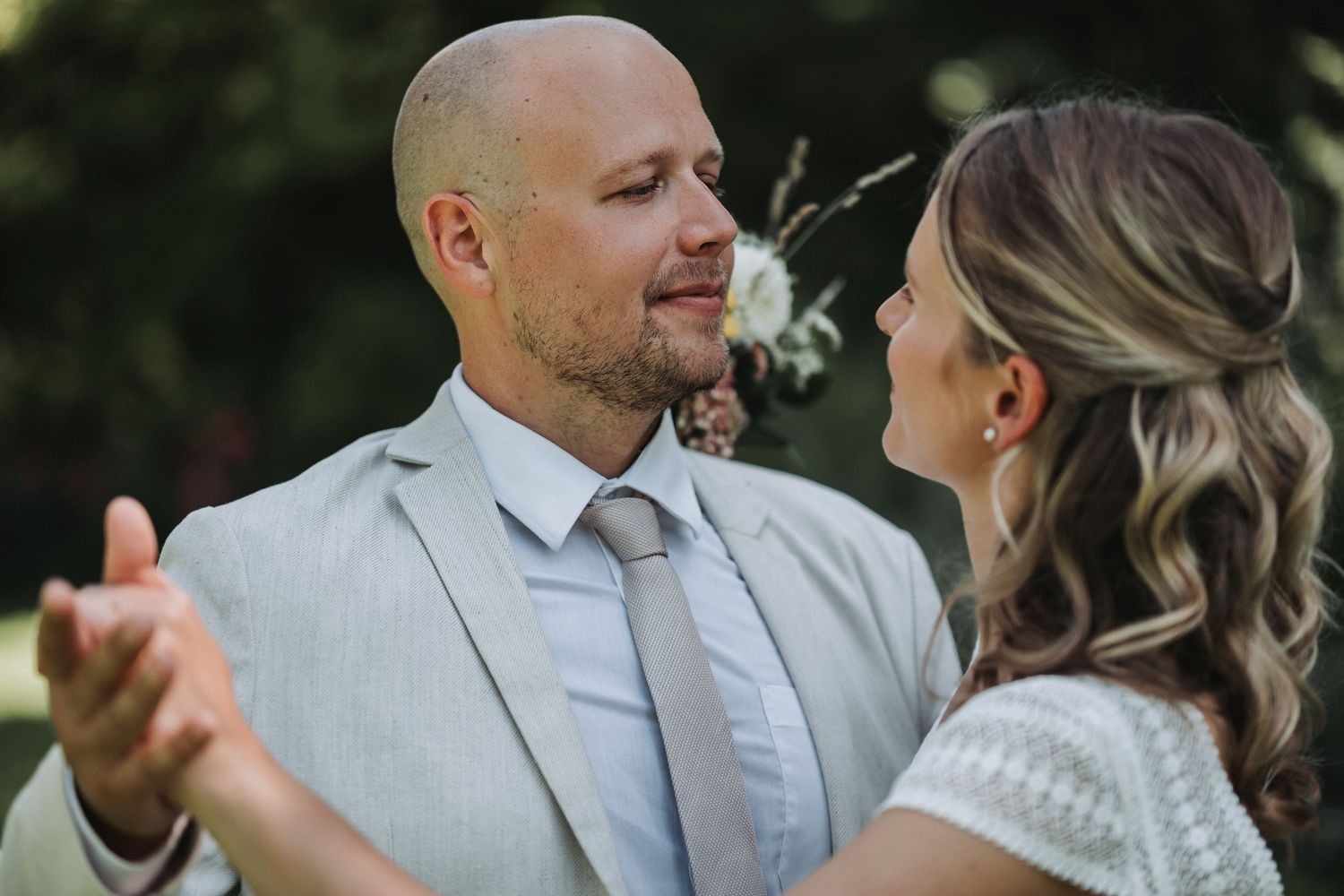 A romantic couple shares tender moments during an outdoor wedding photoshoot in a natural setting.
