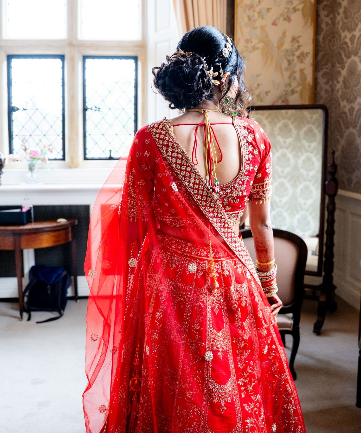 Back view of Indian bride in red lehenga showing intricate embroidery and open back blouse design.