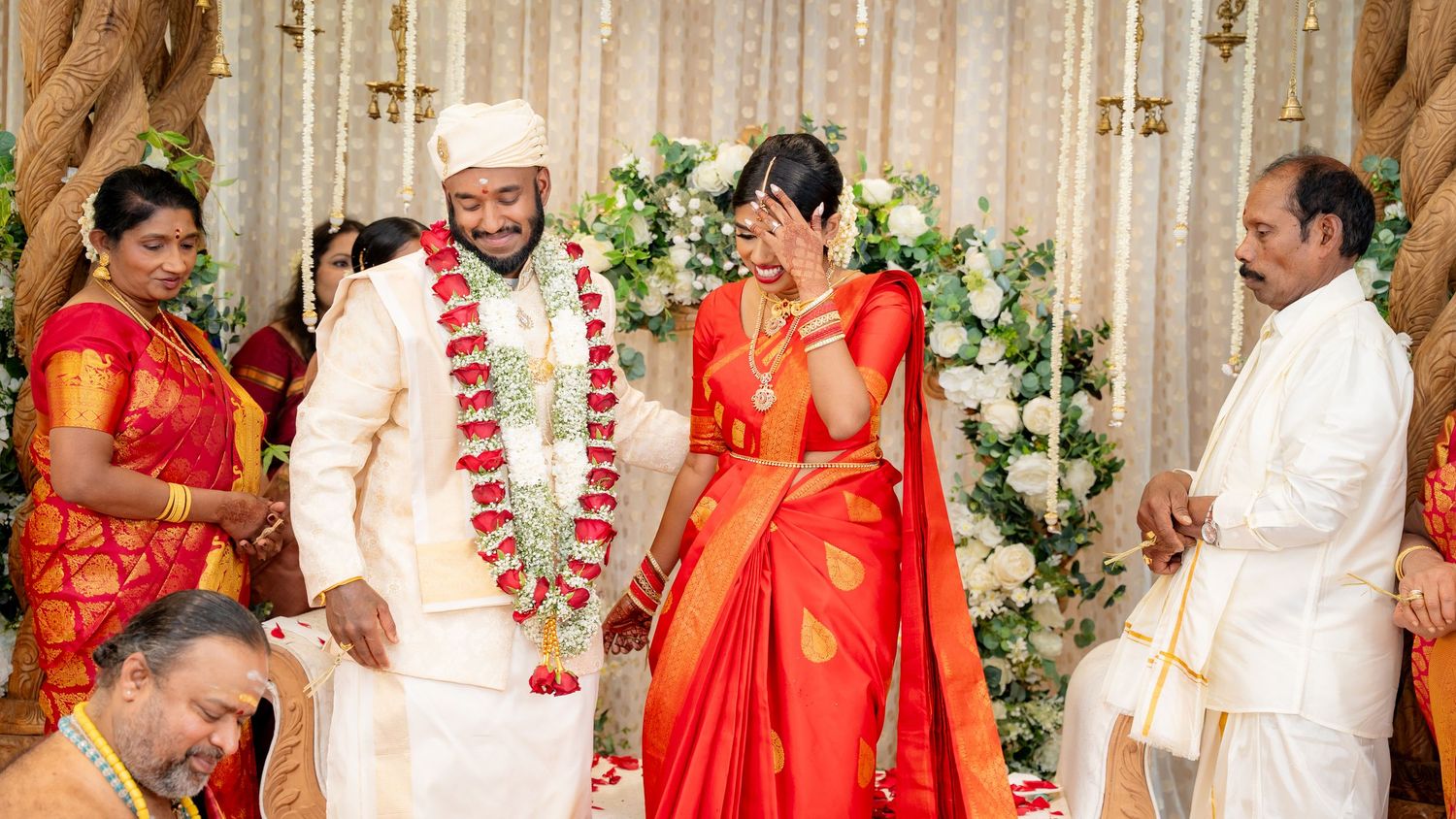 Laughing South Indian newlywed couple in traditional wedding attire share a joyful moment on the mandap.