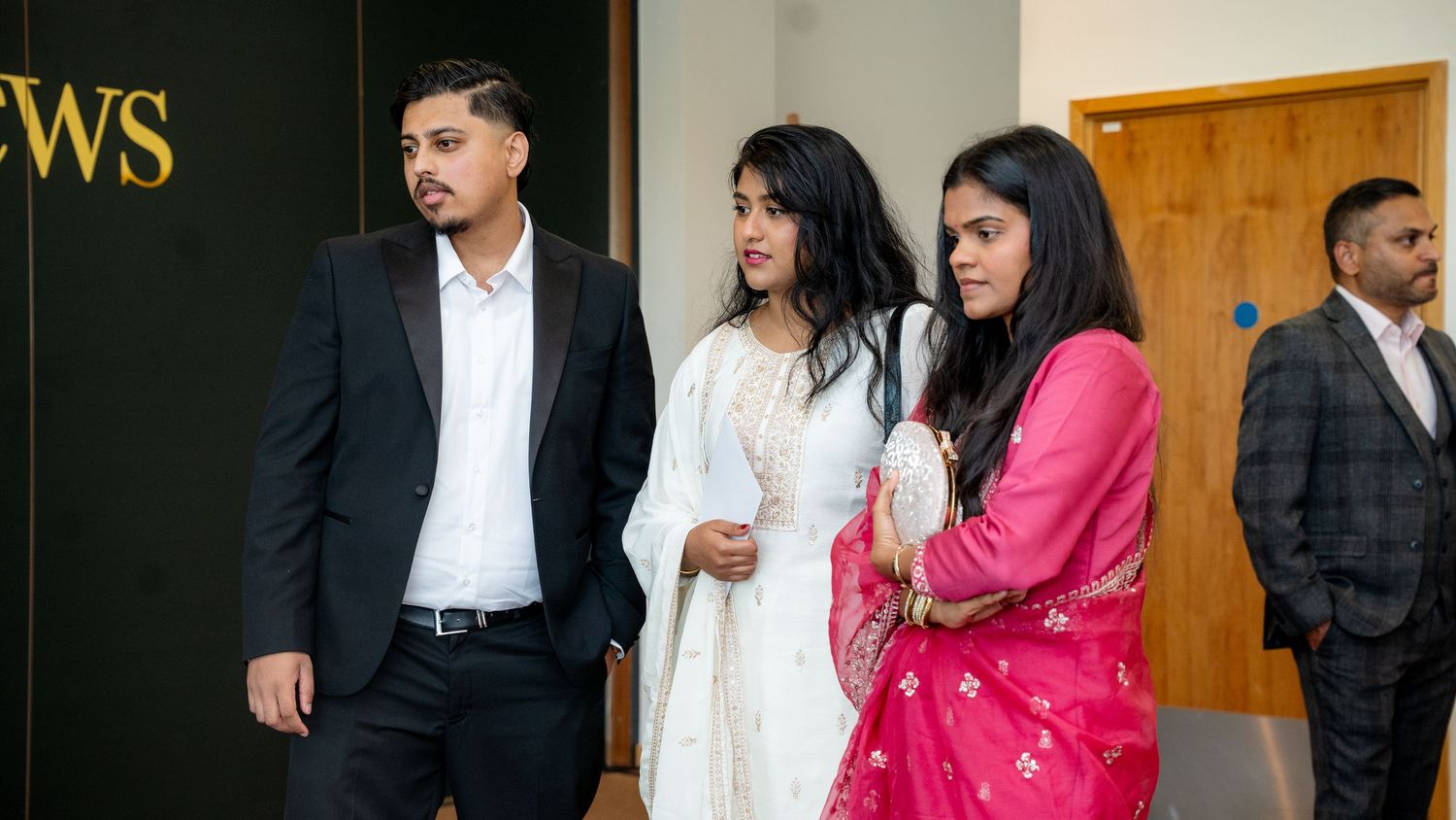 Guests in traditional Indian and formal attire mingling at an indoor wedding celebration.