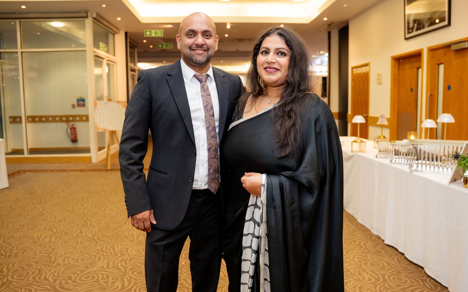 Couple posing together in formal attire at an elegant wedding reception venue.