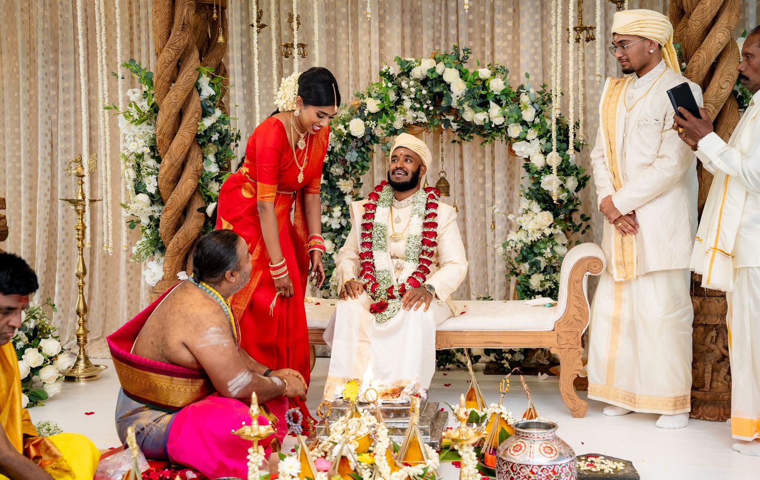 South Indian bride and groom smile during traditional Hindu wedding rituals at decorated mandap.