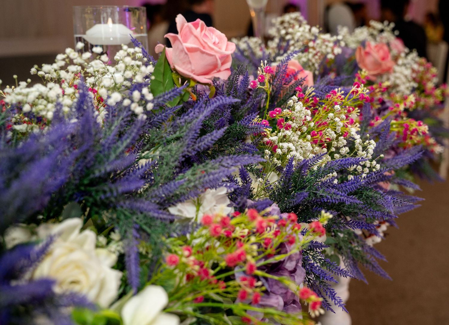 Beautiful wedding table centerpiece featuring purple lavender, pink roses, and white gypsophila flowers.