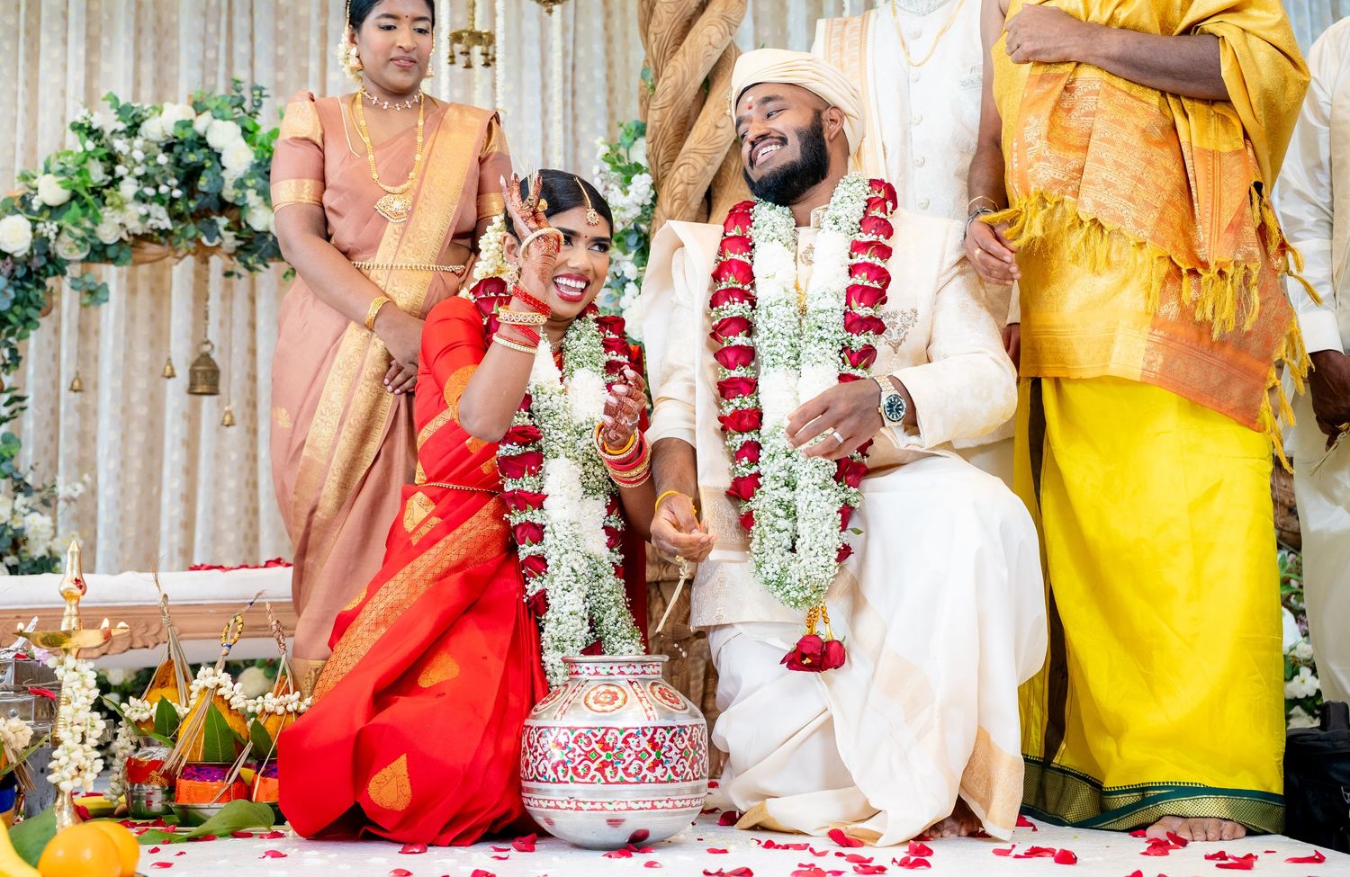 Traditional Indian wedding ceremony with bride and groom performing rituals surrounded by family members in traditional attire.