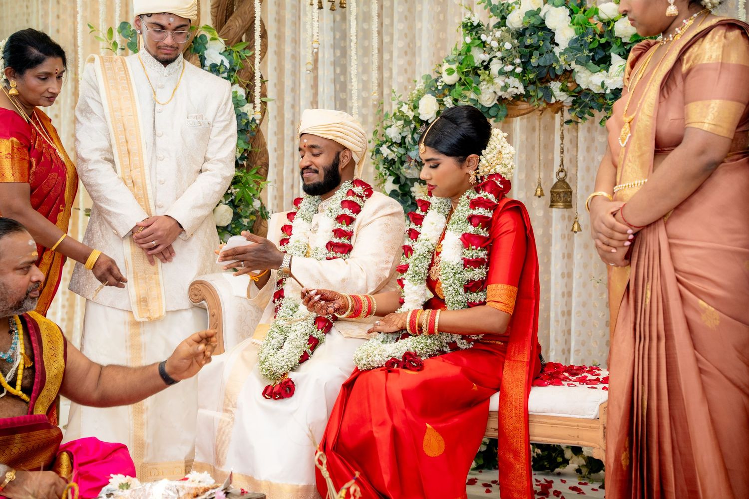 Bride and groom exchange garlands during a traditional South Indian Hindu wedding ceremony on a decorated mandap.