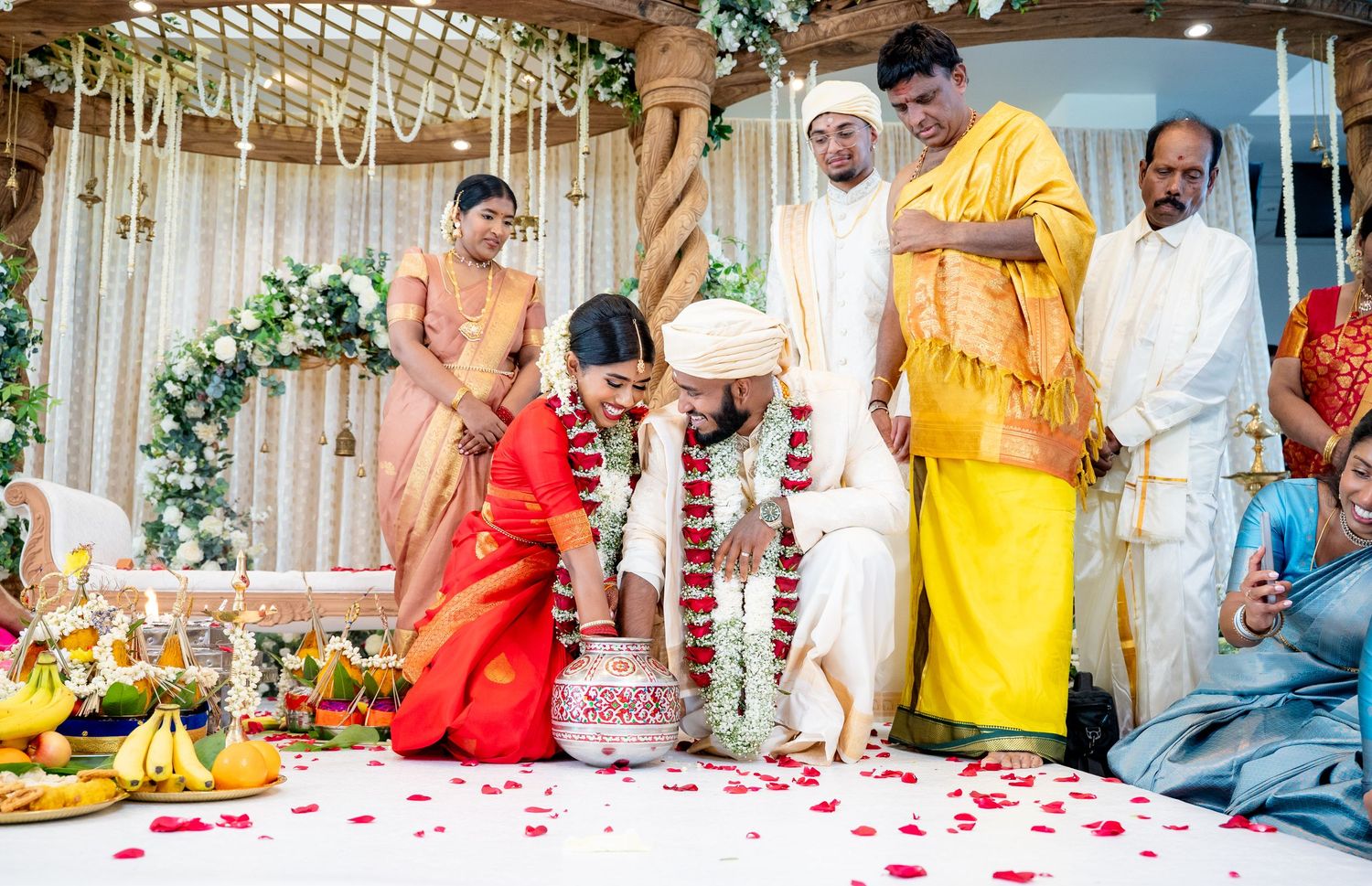 Hindu wedding ritual with bride and groom performing sacred ceremony at flower-decorated mandap.