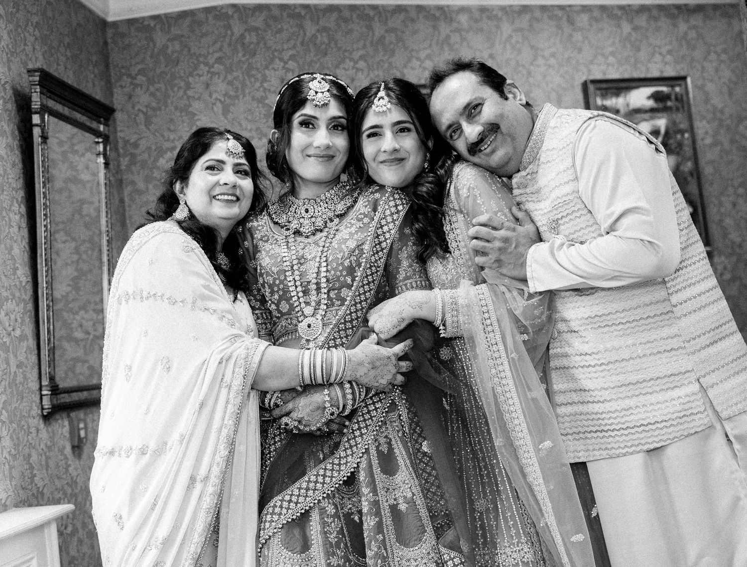 Black and white photo of Indian bride with family in traditional wedding attire.