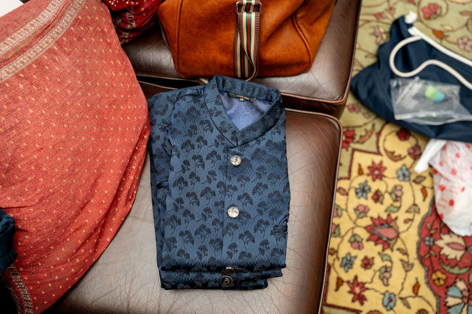 Folded navy blue floral print shirt displayed in an open suitcase with colorful clothing and accessories.