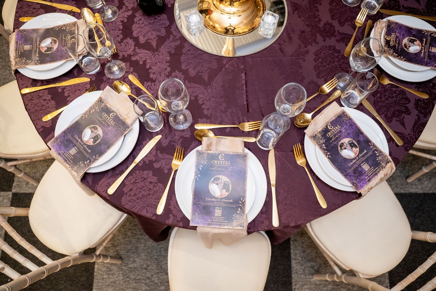 Aerial view of an elegant wedding reception table with purple damask cloth, gold cutlery, and purple place settings.