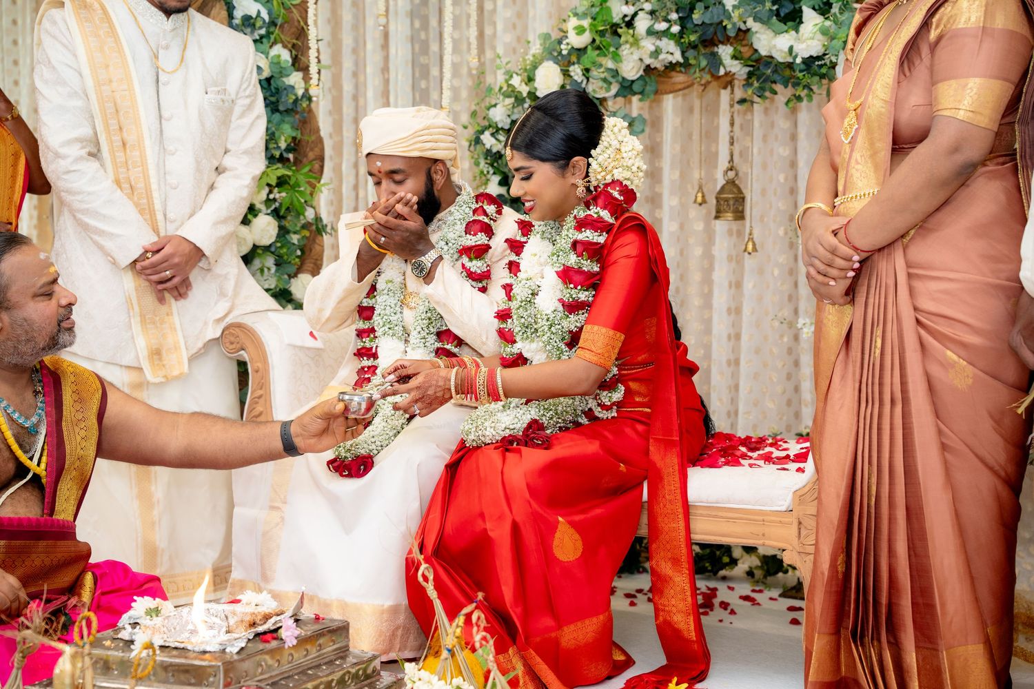 Bride and groom receive blessings during traditional South Indian wedding ceremony with ritual offerings.