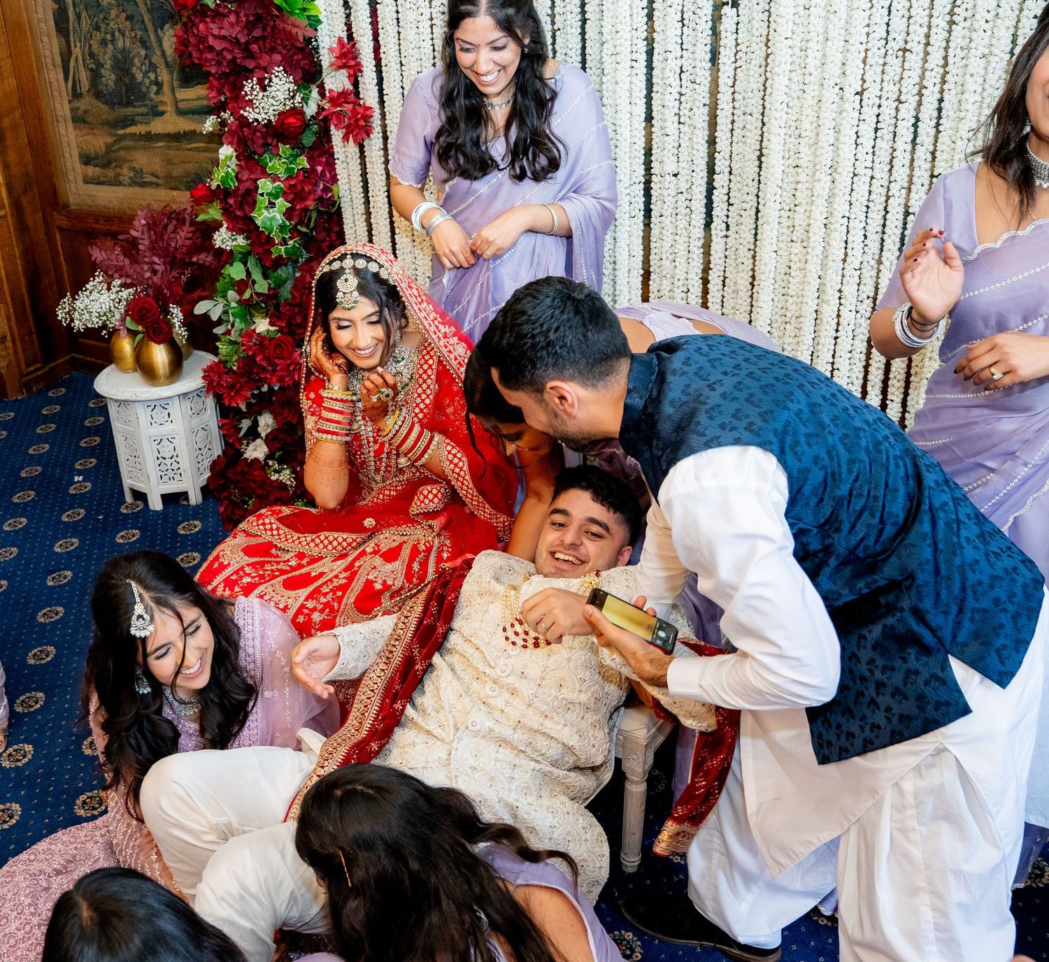 Traditional South Asian wedding ceremony with bride in red lehenga surrounded by joyful family members celebrating together.