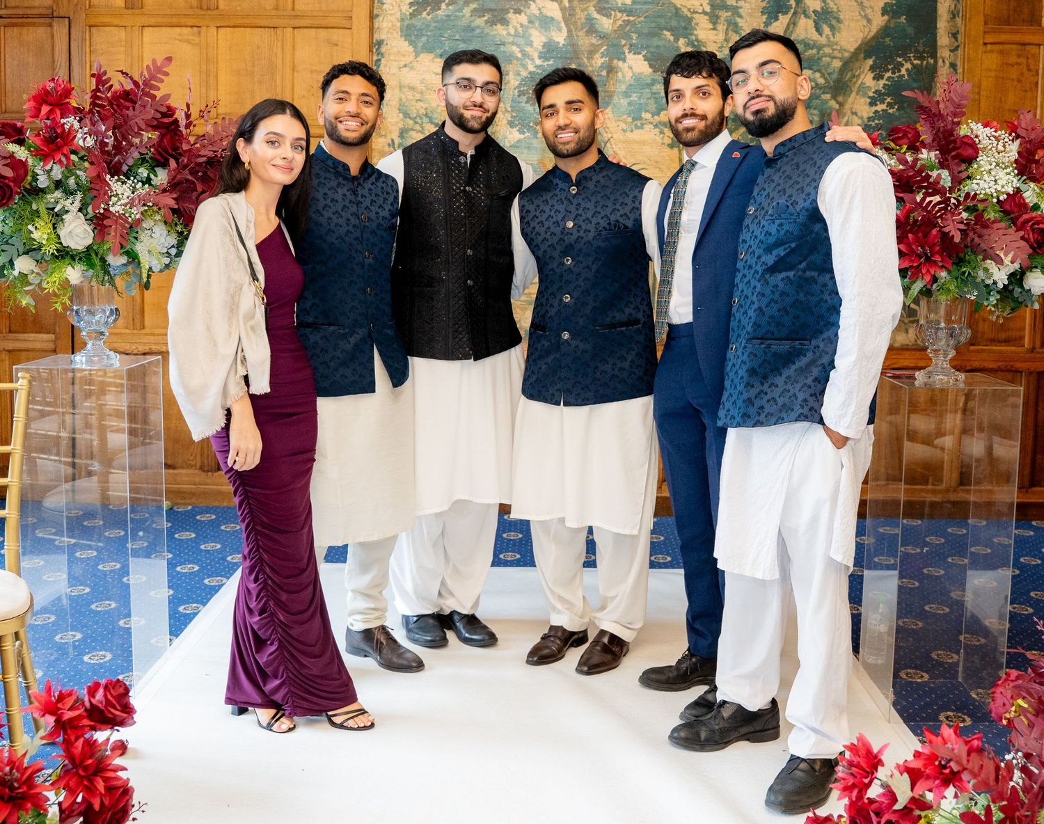 Group of young South Asian wedding guests in coordinating navy and white outfits posing together.