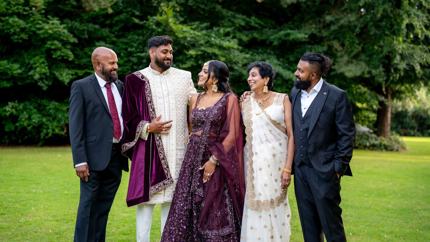 South Asian wedding group portrait with groom in sherwani and guests in traditional and formal attire.