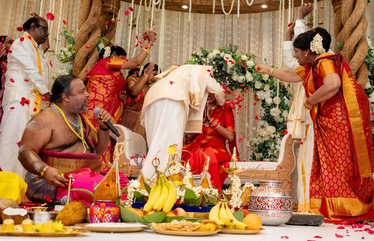 Traditional Hindu wedding blessing ceremony with rose petals being showered on couple at decorated mandap.