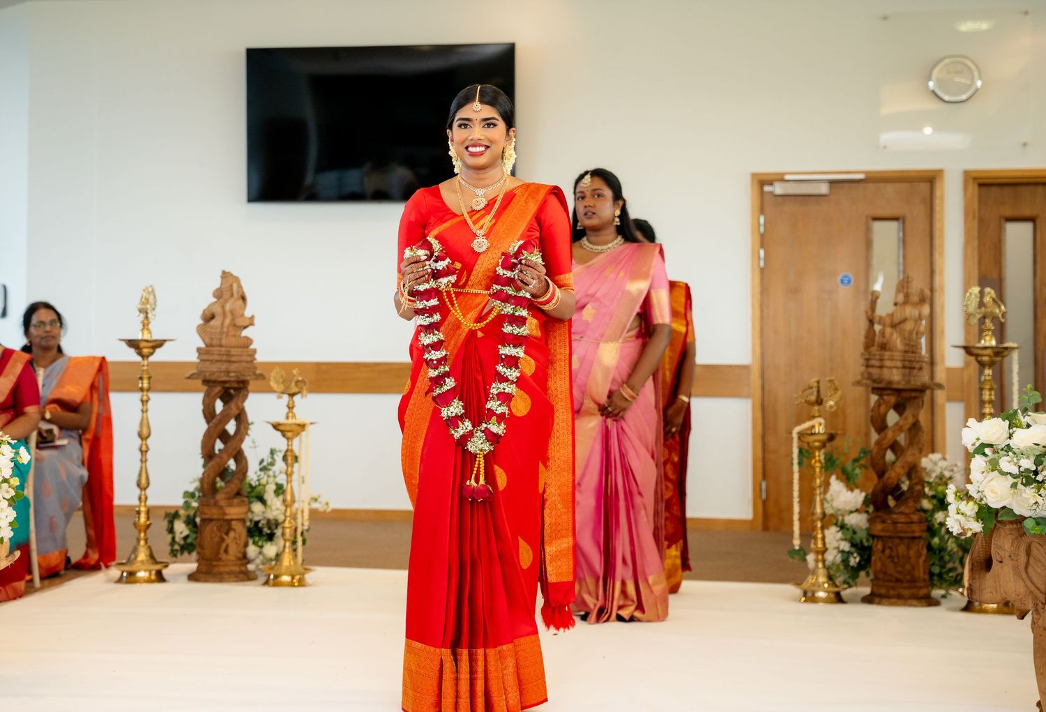 Bride in red and gold Kanjivaram saree walking down the aisle at a traditional Tamil Hindu wedding.