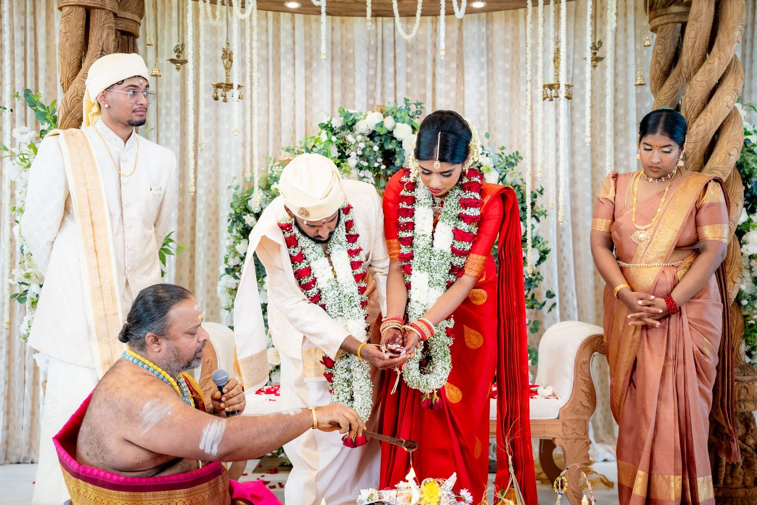 Traditional Hindu wedding ceremony with couple performing rituals at decorated mandap with guests.