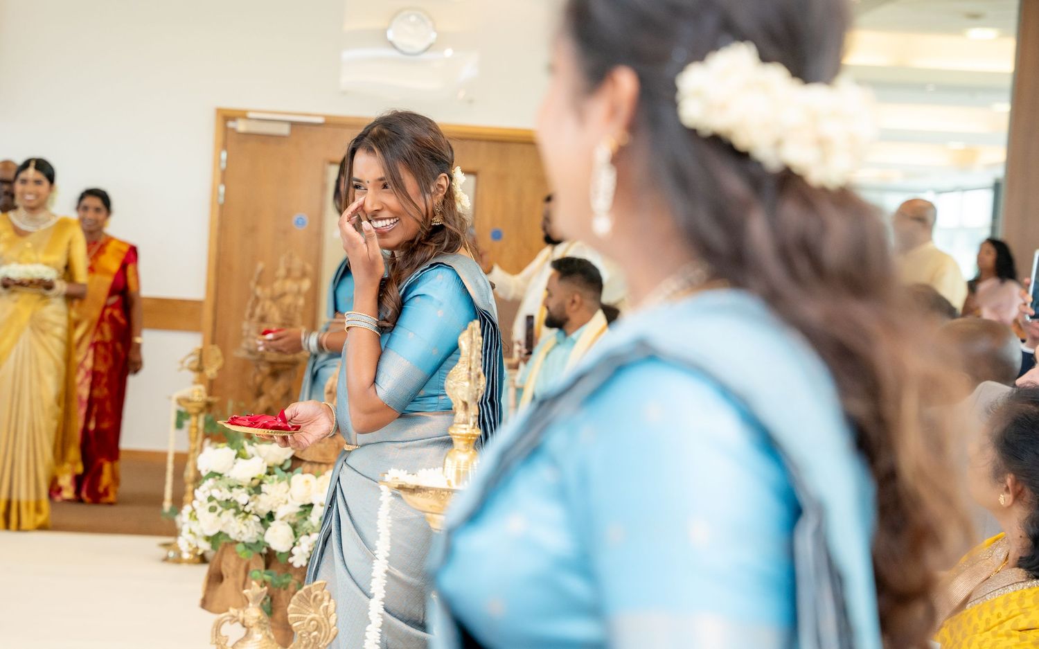 Women in blue traditional attire holding flowers during a cultural ceremony or celebration.