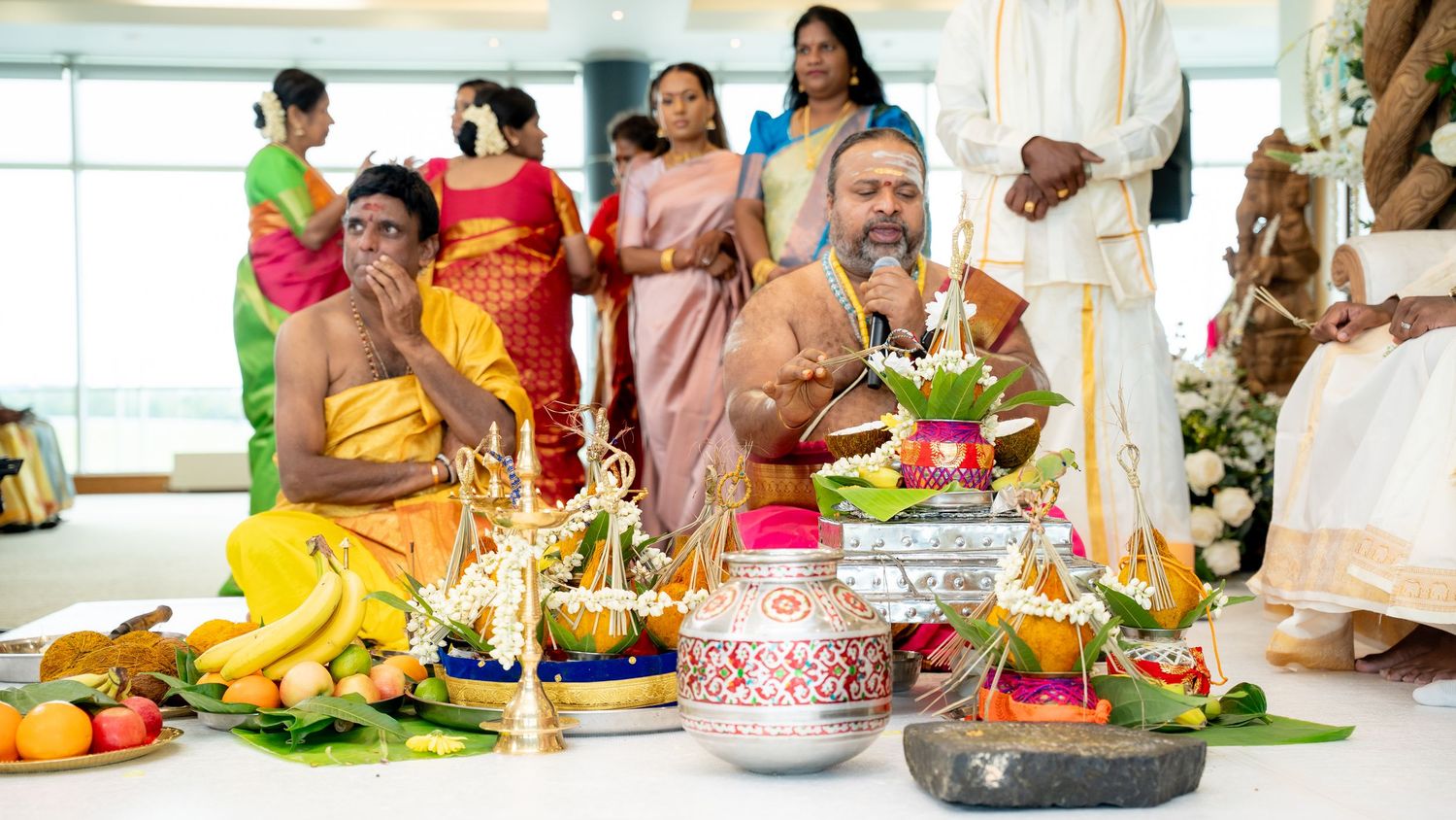 Hindu wedding priests perform sacred rituals surrounded by traditional offerings and guests.