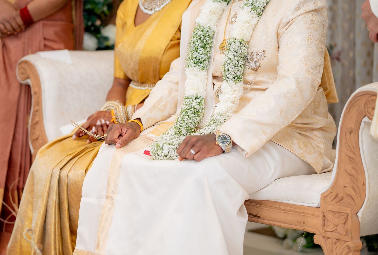 Close-up of Hindu bride and groom in traditional wedding attire holding hands during sacred ceremony rituals.