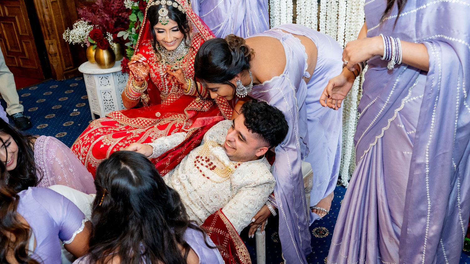 Emotional Indian wedding moment with bride in red lehenga surrounded by bridesmaids.