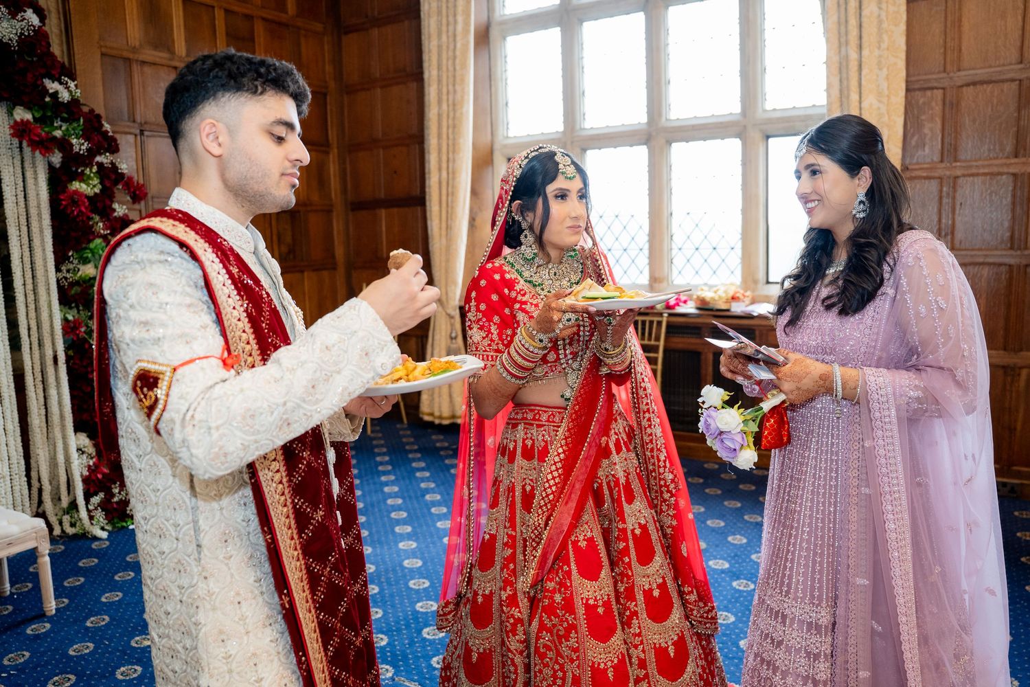 Indian bride and groom exchange items during a traditional wedding ceremony with a female officiant.