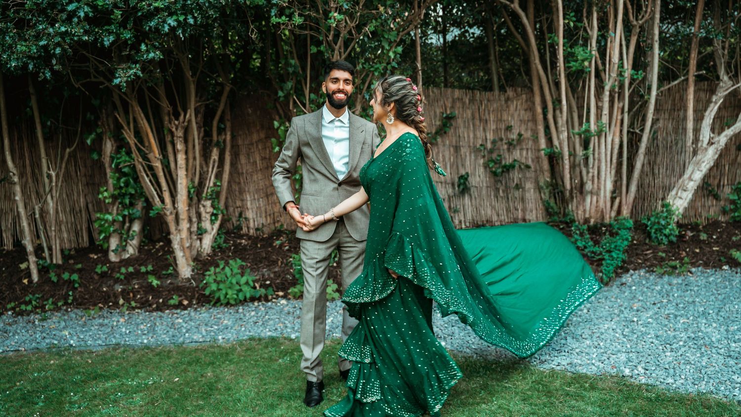Couple dancing outdoors with bride in flowing emerald green embroidered saree.