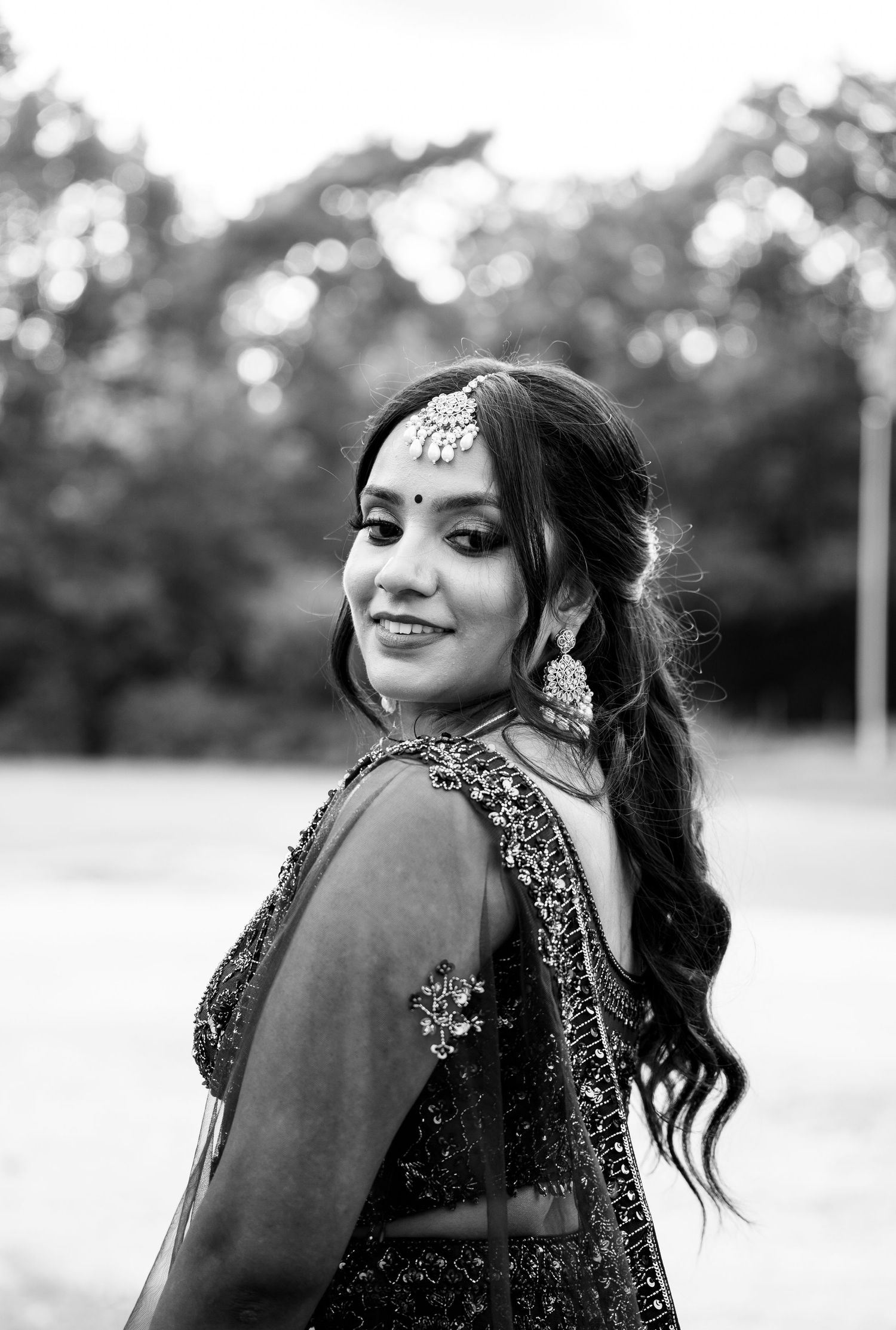 Black and white portrait of a beautiful Indian bride wearing maang tikka and ornate jewelry.