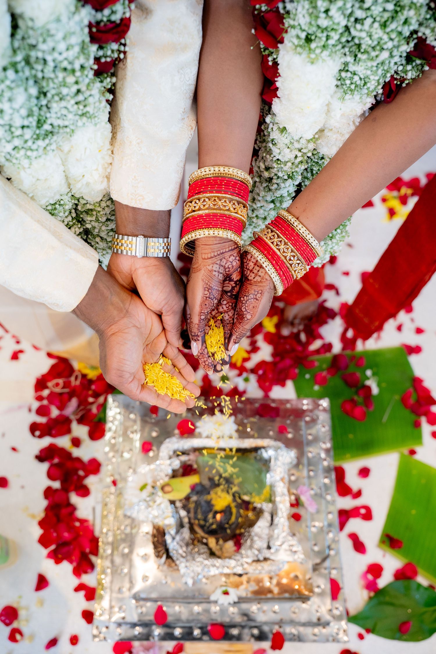 Close-up of bride and groom hands offering yellow turmeric during traditional Hindu wedding ceremony ritual.